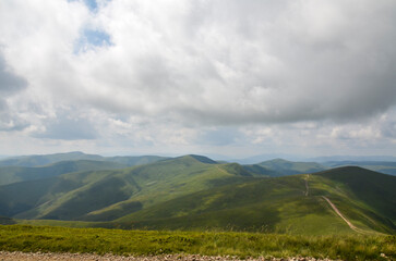 Vast green hills stretch under cloudy skies, offering a breathtaking view of nature's beauty. Svydovets ridge, Carpathian Mountains, Ukraine