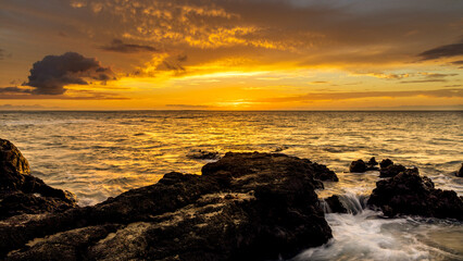Golden Sunset Over Ocean Waves and Black Lava Rocks in Hawaii”