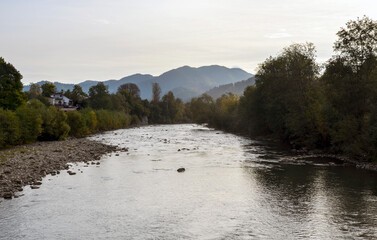 Serene autumn landscape featuring a tranquil Cheremosh river surrounded by lush greenery with...
