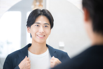 洗面台の鏡の前で朝の身だしなみをチェックする男性