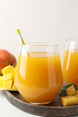 Tasty mango juice in glasses and fresh fruits on white table, closeup