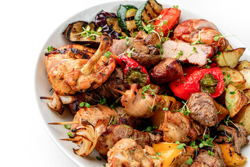 Assorted delicious grilled meat with grilled vegetables on plate isolated on white background. Hot Meat Dishes, top view, close up