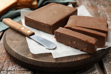 Tasty chocolate butter and knife on wooden table, closeup