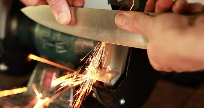 Man sharpening knife with bench grinder indoors, closeup