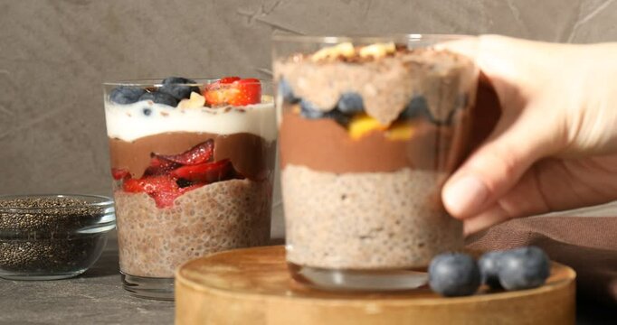 Woman putting glasses with delicious chocolate puddings on table, closeup