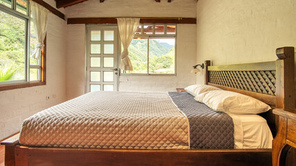 Bright rustic bedroom with wooden bed frame, ceiling beams, and natural light in Ecuador lodge....