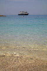 pebble beach and clear water with distant boat