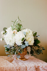 Elegant floral arrangement featuring white roses and greenery on a delicate fabric backdrop