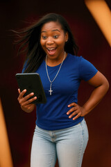 Eccentric African American Woman with Blue T-Shirt and Jeans Holding Digital Tablet and christian pendant rosary