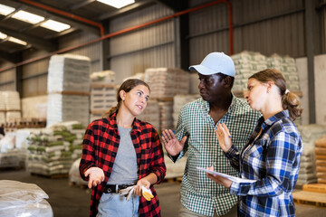 African-american man and caucasian women working in warehouse, talking about job. Employer and...