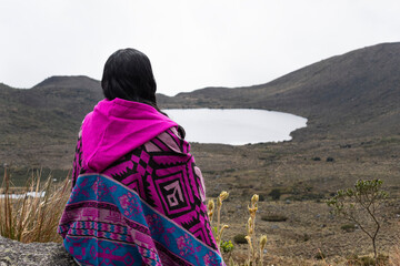 woman sitting on a viewpoint into colombian sumapaz paramo with clkoudy sky at background