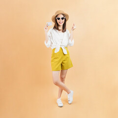 Cheerful beautiful Asian woman holding credit card on beige color background.
