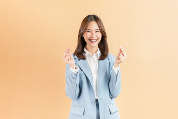 Cheerful beautiful Asian business woman showing mini heart sign on beige color background, love concept.