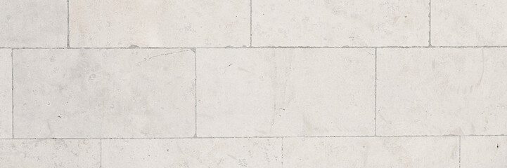 The texture of the wall, lined with light stone blocks. The polished surface of the masonry. Wide panoramic texture for background and design.