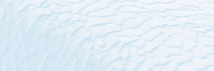 Wide panoramic winter background with snowy ground. Natural snow texture. Wind sculpted patterns on snow surface.