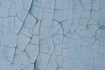 Peeling paint on the wall. Old concrete wall with cracked flaking paint. Weathered rough painted surface with patterns of cracks and peeling. High resolution texture for background and design. Closeup