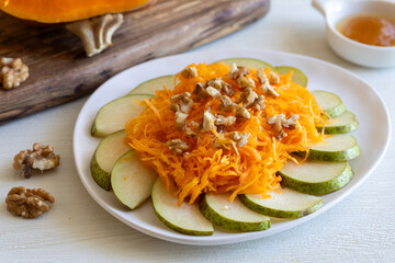 Bright healthy organic autumn harvest salad made of pears, pumpkin, walnut and honey with olive oil on white table. Close up