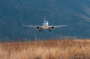 Frontal shot of an airplane about to land in a mountainous area.