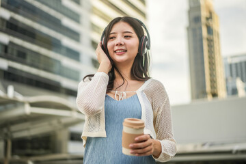 Young asian woman wearing headphones and enjoying music on the urban city, Female listening to music on the town, phone and woman dancing, streaming and enjoying radio, audio or sound podcast