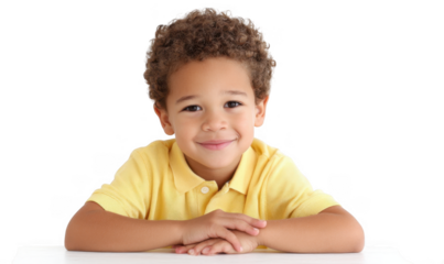 A cheerful young boy with curly hair smiles brightly while resting his arms on a table. set against a clean white background. perfect for family-oriented marketing or educational materials