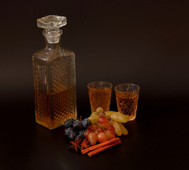 Grappa from different grape varieties with cinnamon and anise in a crystal decanter and two glasses...