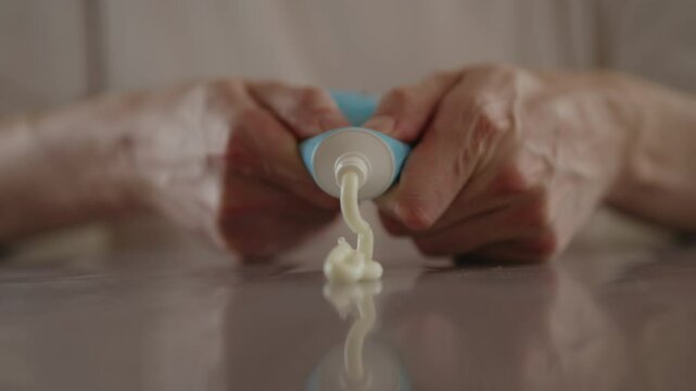 Male hands squeezing moisturizing cream from tube onto table, preparing for skin treatment or cosmetic procedure at home. Concept of beauty and care involved in skincare. Shooting in slow motion.