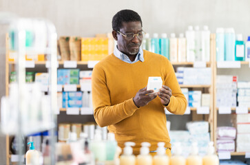 African man buyer select cream, reads composition, finds out information about use of drug....
