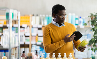 Adult man buyer scanning qr code for shampoo or shower gel in pharmacy