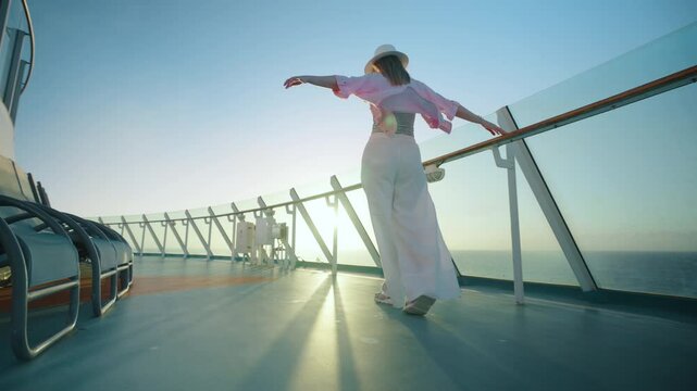 A woman joyfully enjoys her moment on the cruise ship deck, immersed in a vibrant sunset, wearing breezy clothing and a stylish hat that embodies the essence of a perfect vacation