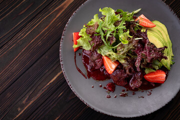 Warm liver salad with avocado, strawberry, and greens