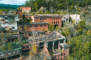 An abandoned mining and processing facility sits in disrepair, with crumbling structures overtaken...