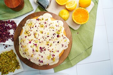 Baking a Persian Love Cake with rose petals, pistachios, citrus and exotic spices like cardamom.  Dessert cake topped with a glaze and sprinkled with rose petals and crushed pistachios.  Love cake.