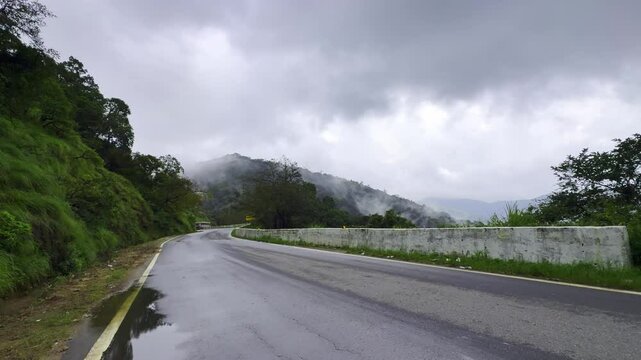 Scenic road through winding mountain road surrounded by rainy tropical forest in charmadi karnataka india