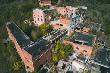 An abandoned mining and processing facility sits in disrepair, with crumbling structures overtaken...
