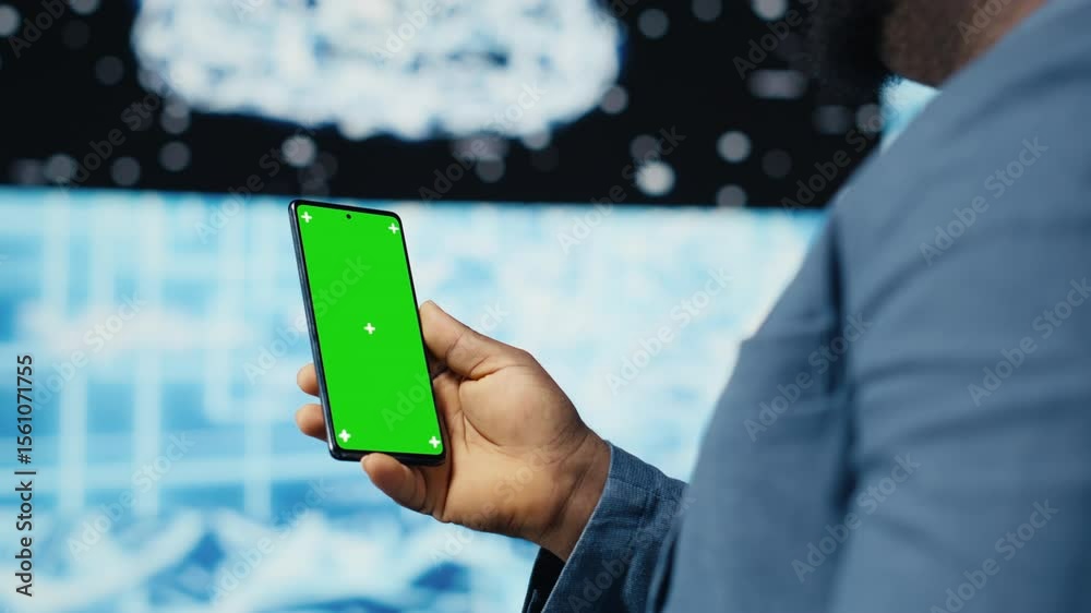 Poster focused black it professional looks at phone with green screen, standing in a digital artificial int