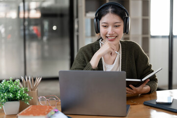 Hipster teen girl school student  wear headphone write notes watch video online webinar learn on laptop elearning course video conference