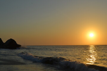 Beautiful sunset on the beach in Santa Marta, Colombia. The golden reflections on the water, clear...