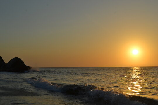 Beautiful sunset on the beach in Santa Marta, Colombia. The golden reflections on the water, clear skies and gentle waves bring summer and paceful vibes.