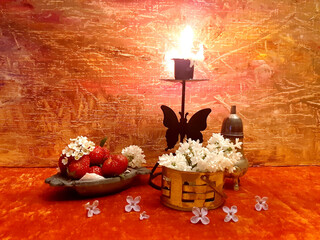 Candle in a candlestick, bloom flowers, flower petals, strawberry,  apple. Exquisite photo still...