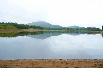 Panoramic morning view of a calm lake reflecting the serene mountain landscape under a vast sky with soft clouds