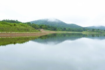 Mountain lake panorama reflecting the summer sky and forest trees, a calm and peaceful nature view