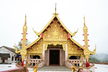 A beautiful ancient Thai Buddhist temple showcases stunning architecture and cultural heritage under a golden roof against the sky.