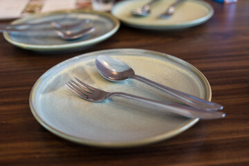 Empty plate spoon and fork on wood table in restaurant
