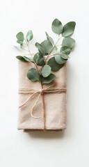 Beige linen napkins tied with twine, adorned with eucalyptus sprigs