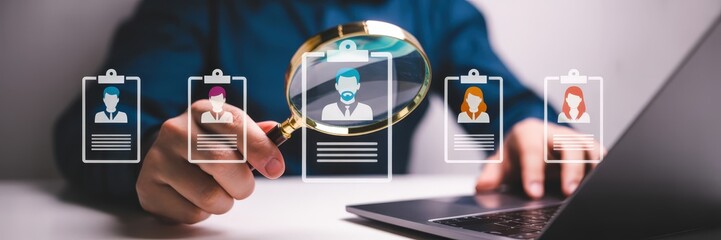 Person's hands examining digital resumes on a laptop.