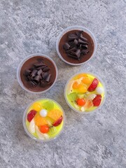 Top view of colorful dessert cups with two chocolate puddings topped with chocolate curls and two...