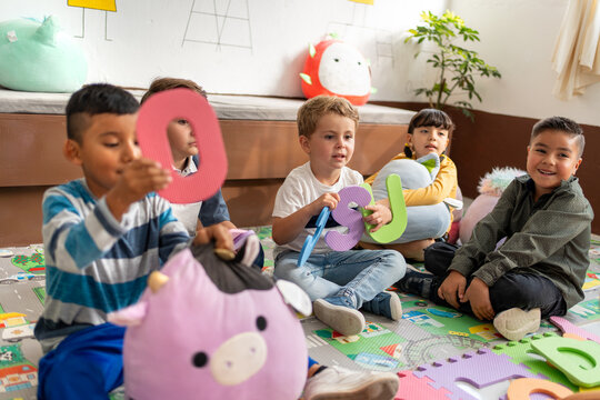 A diverse group of preschool kids playing with foam letters. Kindergarten education, playful learning, and building language skills in early childhood - Powered by Adobe