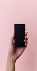 Hand holding a black rectangular case against a pastel pink background