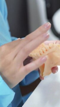 Dental prosthesis in the hands of the doctor close-up. Dentist holding ceramic dental bridge. Front view of complete denture. Dentistry conceptual photo. Prosthetic dentistry. False teeth