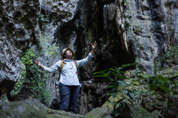 A joyful hiker stands with arms raised inside a rocky canyon, surrounded by lush vegetation. The scene captures freedom, triumph, and a deep connection with nature during an adventurous journey.